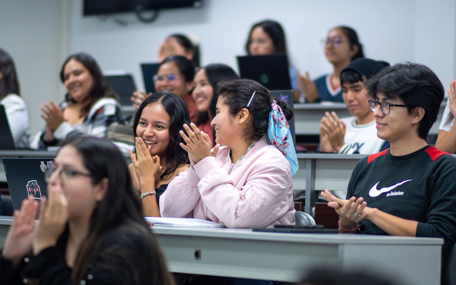 Estudiantes aplauden sentados en un aula