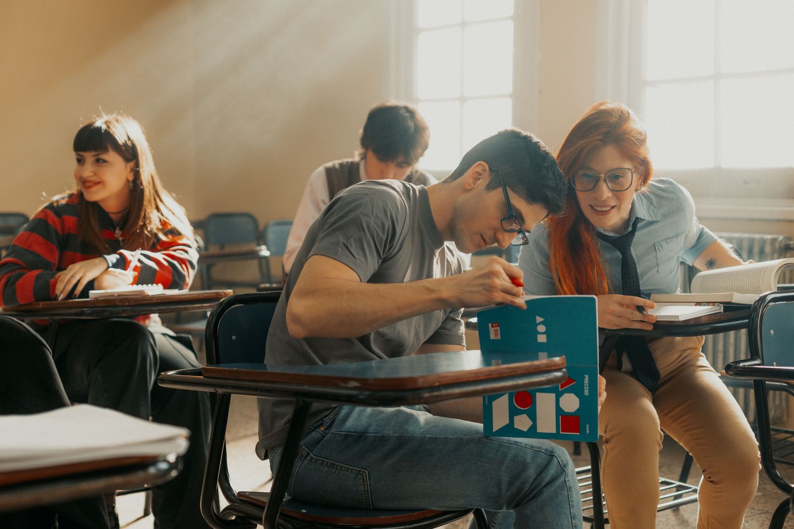 Adultos jóvenes estudian juntos en un aula con luz de tarde