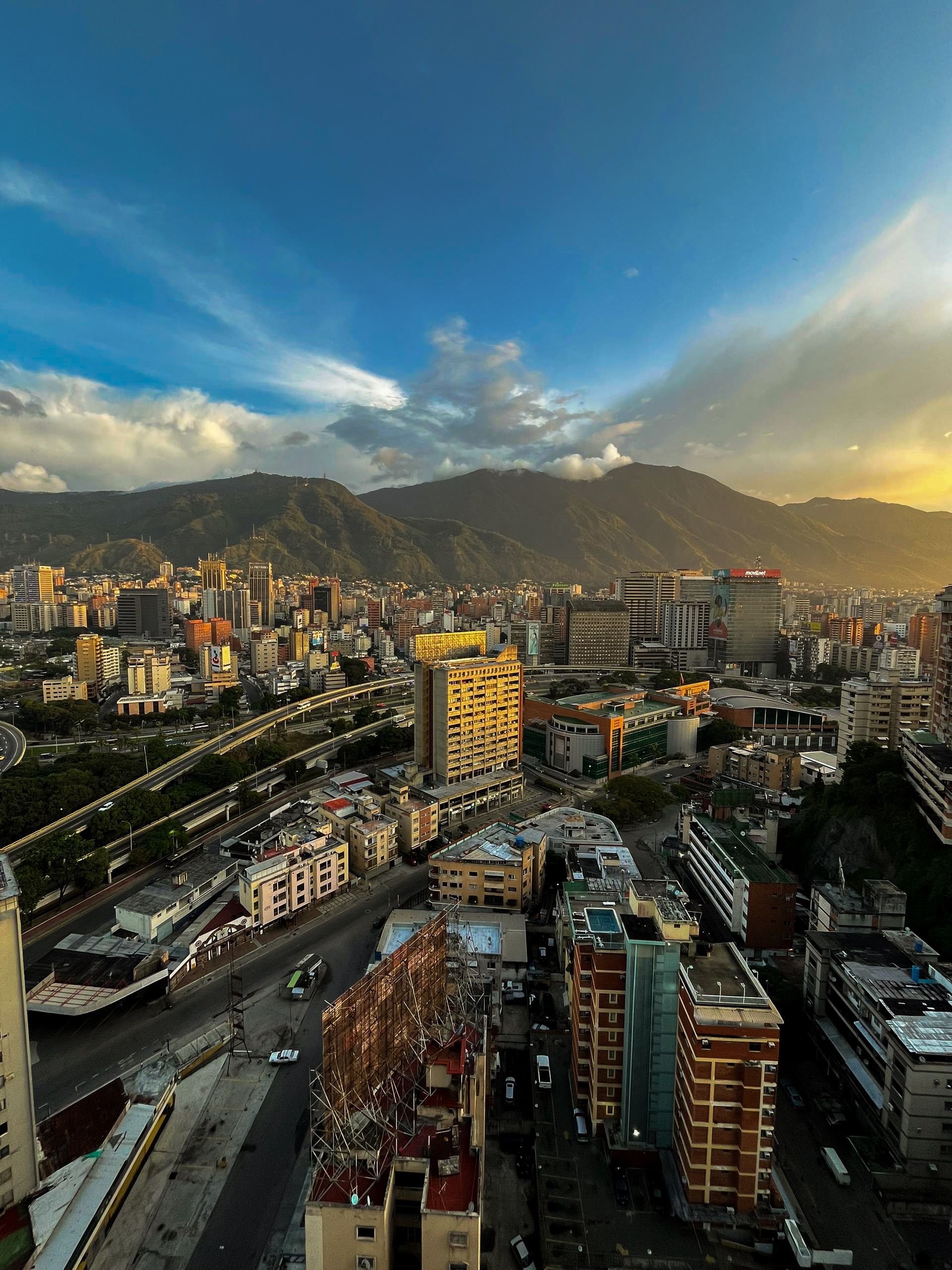 Vista aérea de Caracas al atardecer, con las montañas al fondo