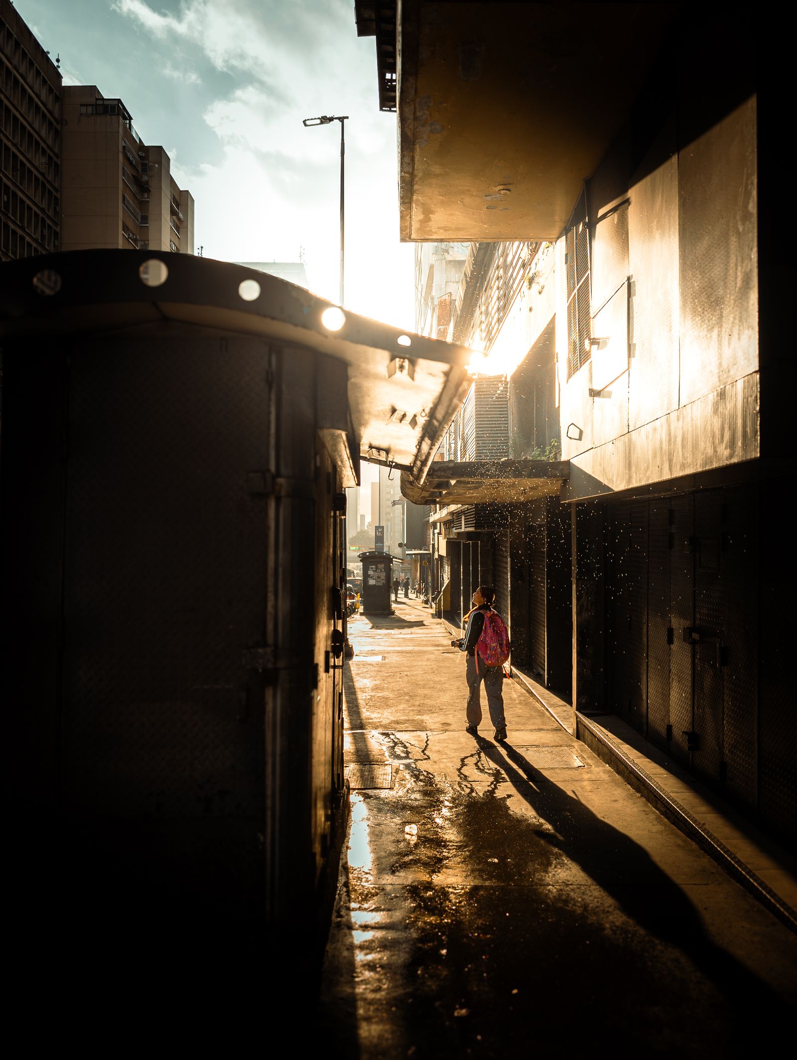 Una persona camina por un callejón de Caracas a la hora dorada