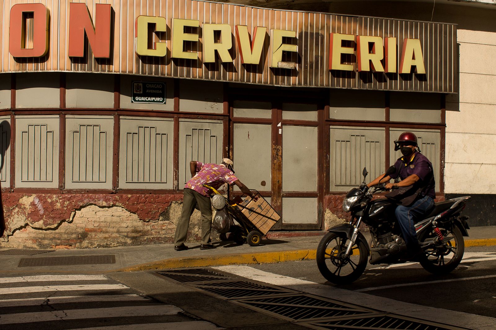 Un motorizado y un vendedor en una calle de Caracas